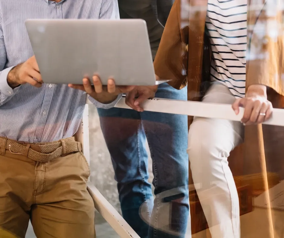 Two people standing side by side and looking at an open laptop together