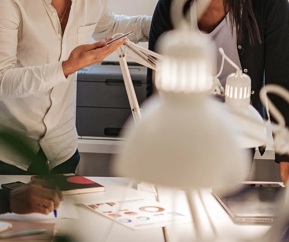 Besprechung im Büro: Auf dem Tisch liegt eine ausgedruckte Auswertung mit Diagrammen, daneben wird mitgeschrieben